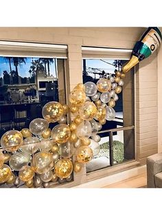 the balloon arch is decorated with gold, silver and white balloons in front of a window