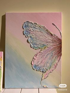 a painting of a butterfly on a pink and blue background next to two small paintings