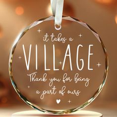 a glass ornament that says it takes a village thank you for being a part of ours