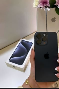 a woman holding an iphone in her hand next to a flower vase and phone case