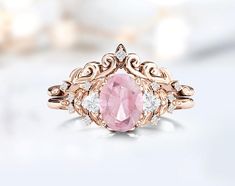 a pink diamond ring sitting on top of a white surface with diamonds around the band