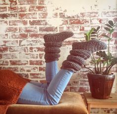 a woman laying on her back in front of a brick wall and potted plant