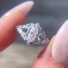 a close up of a person's hand holding an engagement ring