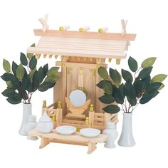 a dollhouse with some plants and plates on the table in front of it,