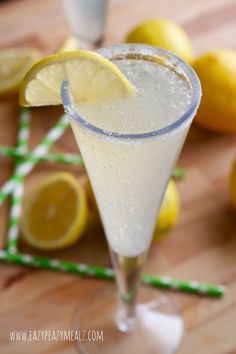 a glass filled with lemonade sitting on top of a wooden table next to sliced lemons