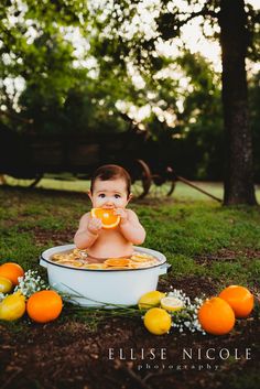 a baby sitting in a tub with oranges around it