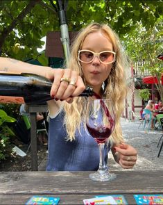 a woman pours red wine into a glass