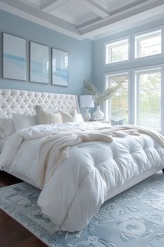 a large white bed sitting in a bedroom next to a window with two pictures on the wall