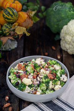 a bowl filled with broccoli, cauliflower and nuts on top of a wooden table