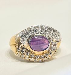 a yellow gold ring with an amethorate surrounded by diamonds