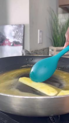 a person stirring food in a pan with a blue spatula on the stove top