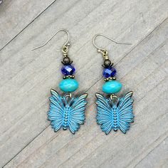 a pair of earrings with blue beads and a butterfly