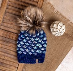 a knitted hat with a pom - pom sits on top of a rug