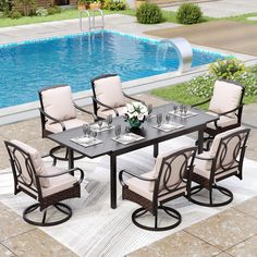 an outdoor dining table with six chairs around it and a pool in the back ground