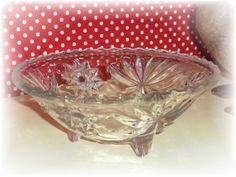 a glass bowl sitting on top of a table next to a red polka dot pillow