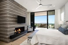 a bedroom with a bed, fireplace and large glass doors that open to the outside