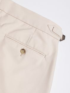 the bottom view of a pair of beige pants with buttons on each side and one button at the end