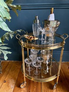 a gold bar cart with wine glasses on it