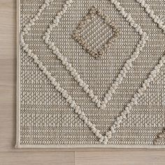 an area rug on the floor with white and beige colors, including squares and dots