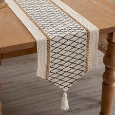 a table runner with tassels on it sitting on top of a wooden table