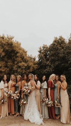 a group of women standing next to each other in front of some trees and bushes