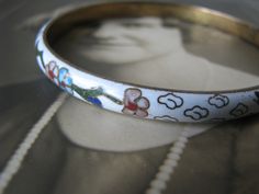 This is a beautiful vintage white cloisonne bracelet from the 1970's. It measures 7mm wide x 3mm thick. It is 2 5/8'' across on the inside, and 8'' around the inside. It is in good vintage condition with a Shabby Oriental grace. Perfect as a gift to a bride, or add it to your sweet collection. Antique White Bracelet Jewelry, White Antique Bracelet Jewelry, White Antique Bracelet, Collectible White Bracelet Jewelry, Retro White Round Jewelry, White Retro Enamel Jewelry, Retro White Enamel Jewelry, Vintage Enamel Bangle As A Gift, Vintage Enamel Bangle For Gift