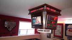 an old fashioned arcade machine hanging from the ceiling in a room with red walls and posters on the wall