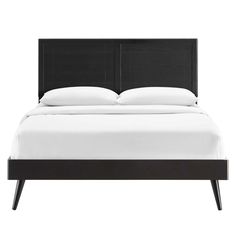 a bed with white sheets and black headboard