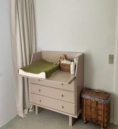 a baby crib next to a dresser with a stuffed animal on top of it