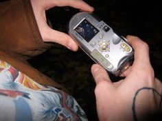 a person holding a silver cell phone in their left hand and looking at the screen