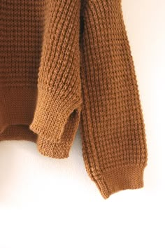 a brown sweater hanging on a white wall