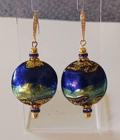 a pair of blue and gold earrings hanging from hooks