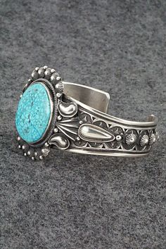 This stunning Kingman turquoise and sterling silver bracelet was made by Navajo silversmith Derrick Gordon. The back is signed Derrick and stamped Sterling.Size: 5 3/8" (will fit up to a 6 1/2" wrist)Gap: 1 1/8"Width: 1 1/2"Cuff Width: 1/2"Free shipping on all orders! We ship with USPS and always include tracking. All orders ship within a day of payment.Returns are accepted up to 30 days after you receive your order. Just send us a message. Our shop offers cash back or store credit. The item mus Bohemian Engraved Turquoise Sterling Silver Bracelet, Bohemian Turquoise Engraved Sterling Silver Bracelet, Western Style Engraved Blue Jewelry, Engraved Turquoise Southwestern Jewelry, Western Sterling Silver Cuff Bracelet With Concho, Southwestern Turquoise Sterling Silver Cuff Bracelet, Southwestern Stamped Turquoise Sterling Silver Bracelet, Southwestern Style Sterling Silver Turquoise Bracelet, Southwestern Engraved Blue Cuff Bracelet