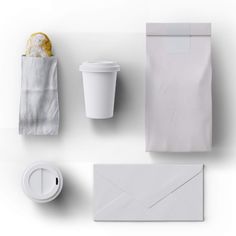 an envelope, coffee cup and other items on a white surface