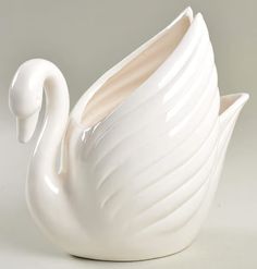 a white swan shaped vase sitting on top of a table