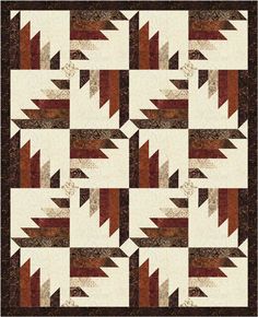 a quilt with brown and white designs on the front, along with an orange border