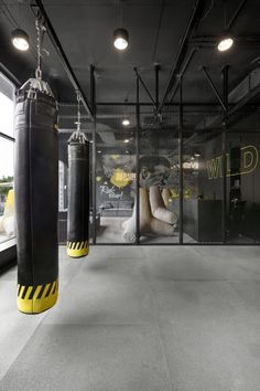 an empty gym with boxing gloves hanging from the ceiling and punching bags on the floor