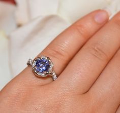 a close up of a person's hand holding a ring with a blue stone