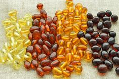 several different types of vitamin capsules on a burlly cloth background, including one yellow and one orange