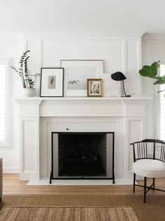 a living room with a fireplace and pictures on the mantel above it in front of a window