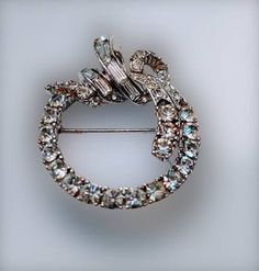 "Sparkling clear rhinestone circle wreath brooch. Graduated round stones, topped with a swirl of bezel set baguettes. I'm not sure if this is white gold or rhodium plated. 1 1/2\" x 1 1/4\" Marked 'CINER©' Other than a touch of wear to the pin, everything is in very good condition. Stones are sparkly and all are present. Thank you for shopping at The Looking Glass Plus!" Elegant Round Brooches For Vintage Events, Vintage Diamond Round Brooches, Elegant Round Brooches With Rhinestones, Elegant Round Rhinestone Brooches, Round Rhinestone Brooches For Formal Occasions, Round Formal Brooches With Rhinestones, Formal Round Brooches With Rhinestones, Formal Round Rhinestone Brooches, Elegant Round Crystal Brooches