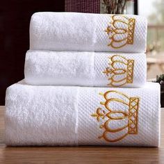 three white towels stacked on top of each other in front of a vase with flowers