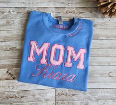 MOM Sweatshirt embroidered stitches with Chenille lettering. Lightweight fleece crew neck sweatshirt. The sweatshirt is available in Light Pink, light blue,  navy blue. HERE'S HOW TO ORDER: 1) Select your sweatshirt color and size from the drop-down menu. 2) Include your name (no more than 12 letters). 3) Include the text for the collar (no more than 20 letters) DETAILS: Cotton/Polyester blend Crew Neck Blue Crew Neck Sweatshirt With Embroidered Logo, Blue Long Sleeve Sweatshirt With Embroidered Logo, Blue Crew Sweatshirt With Embroidered Graphics, Blue Relaxed Fit Sweatshirt With Embroidered Graphics, Blue Relaxed Fit Sweats With Letter Print, Blue Embroidered Text Sweatshirt With Relaxed Fit, Blue Fleece Sweats With Letter Print, Blue Fleece Tops With Embroidered Logo, Light Blue Letter Print Sweatshirt For Fall