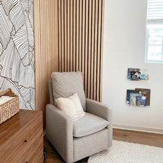 a chair in front of a wall with wood slats on it and a basket next to it