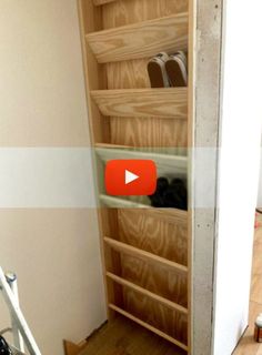 an open closet with shoes and other items on shelves next to a ladder in a room