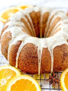 a bundt cake with icing and oranges on a cooling rack