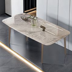 a white marble dining table with gold legs and lights on the wall in front of it