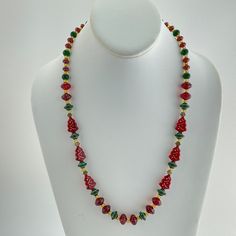 a necklace with red and green beads on a white mannequin