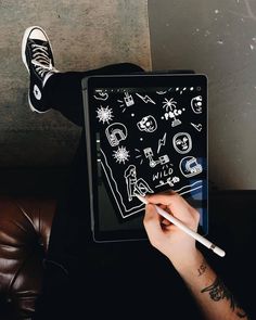 a person sitting on a couch with their feet up while using an electronic device to draw doodles