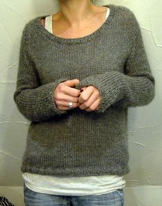 a woman standing in front of a white wall with her hands folded over her chest